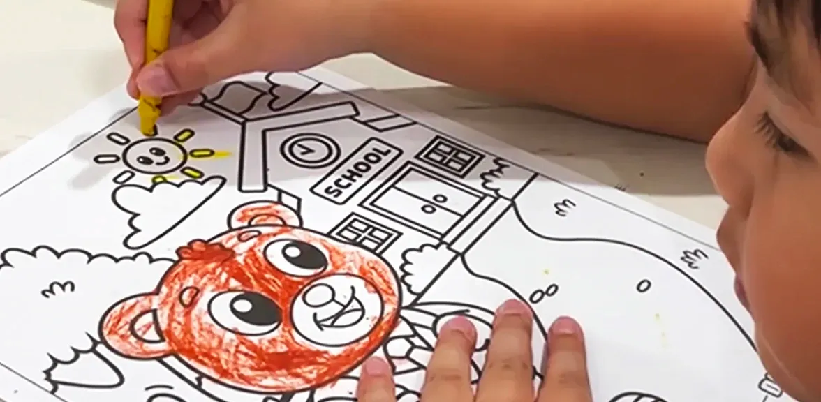 Small hands coloring a bear page with a yellow crayon