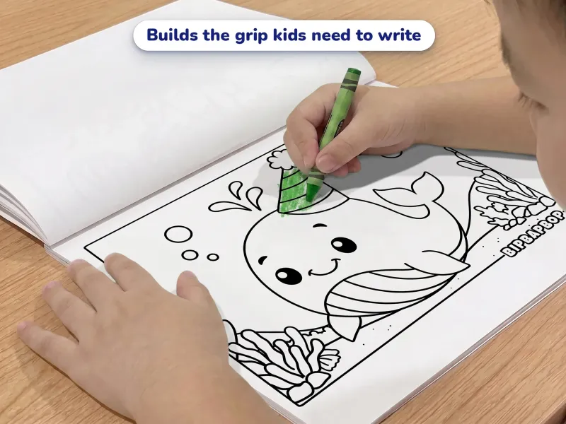 Child with a crayon coloring a picture of a baby whale in a party hat