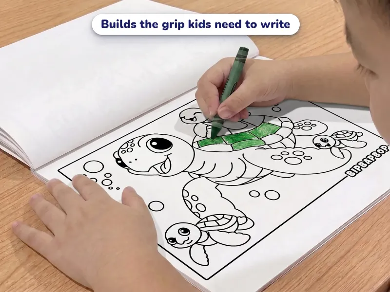 Child with a crayon coloring a picture of a turtle family swimming under the sea