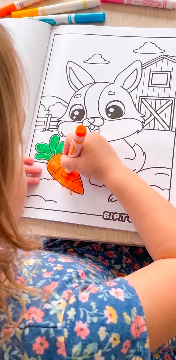A girl coloring a farm animal page with an orange marker